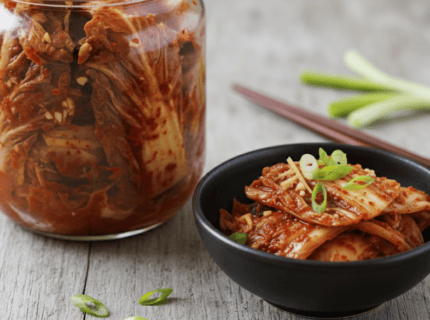 Selbstgemachtes Kimchi im Glas und in einer Schale mit Frühlingszwiebeln